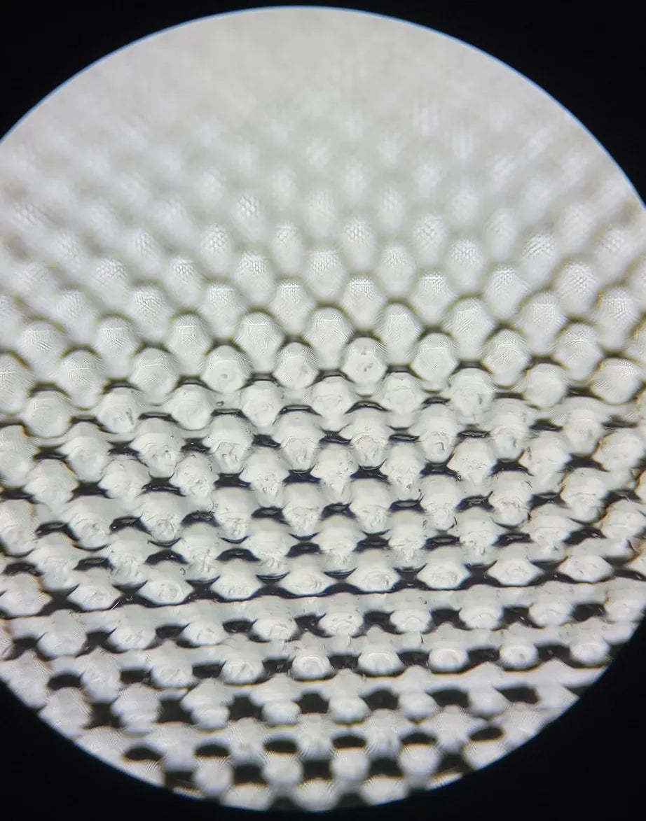 Surface-enhanced quartz under a microscope, an even honeycomb of dimples cut into the surface